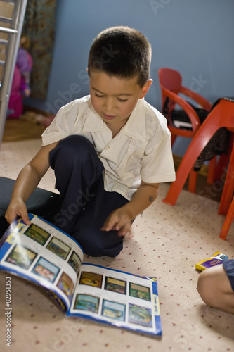 Asian boy reading magazine in bedroom photo