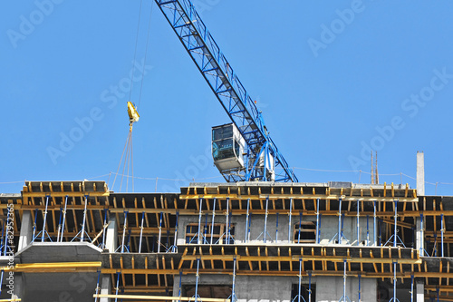 Crane and building construction site against blue sky