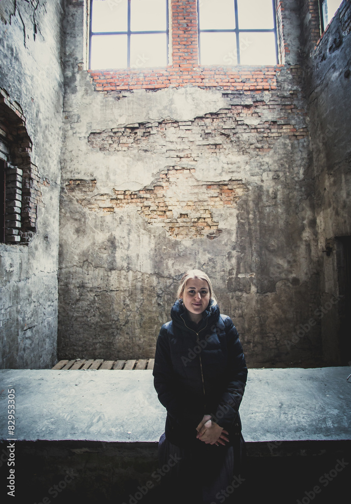 Toned photo of lonely woman posing at grungy abandoned building