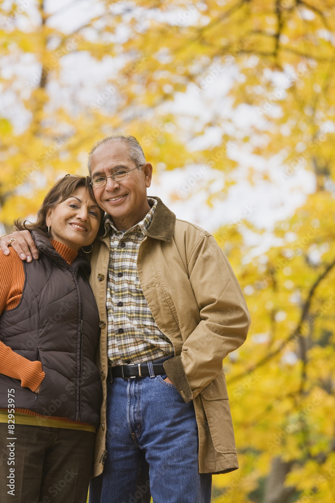 Hispanic couple hugging outdoors in autumn Hispanic couple hugging outdoors in autumn