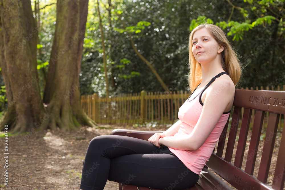 young woman in fitness wear sitting on a bench young woman in fitness wear sitting on a bench