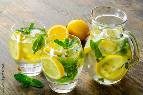 Lemonade in two glass and lemon with mint on the table