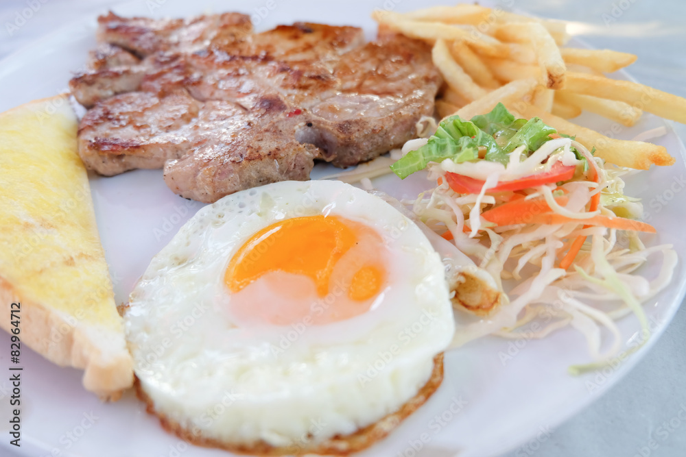 Grilled steaks, French fries, fried egg and vegetables Grilled steaks, French fries, fried egg and vegetables