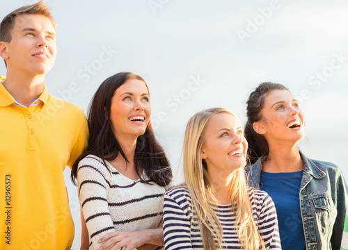 group of happy friends looking up on beach
