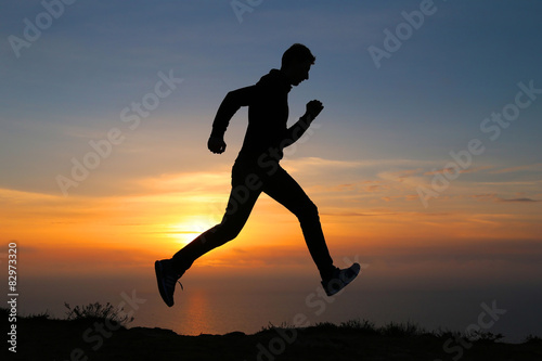 Silhouette of running man against the colorful sky. 