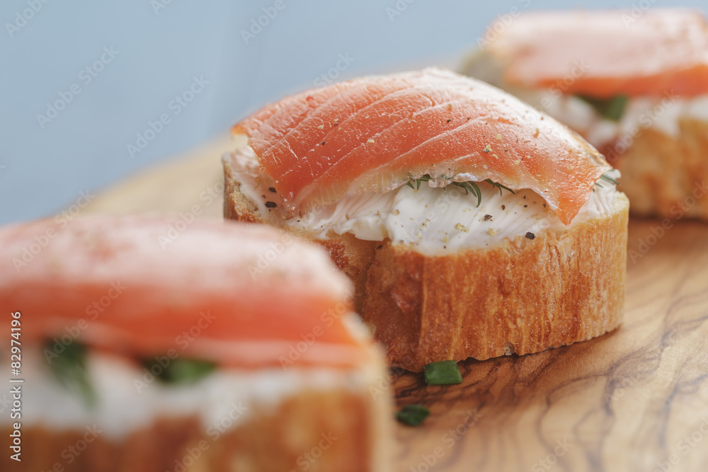 small sandwiches with soft cheese and salmon on wood table small sandwiches with soft cheese and salmon on wood table