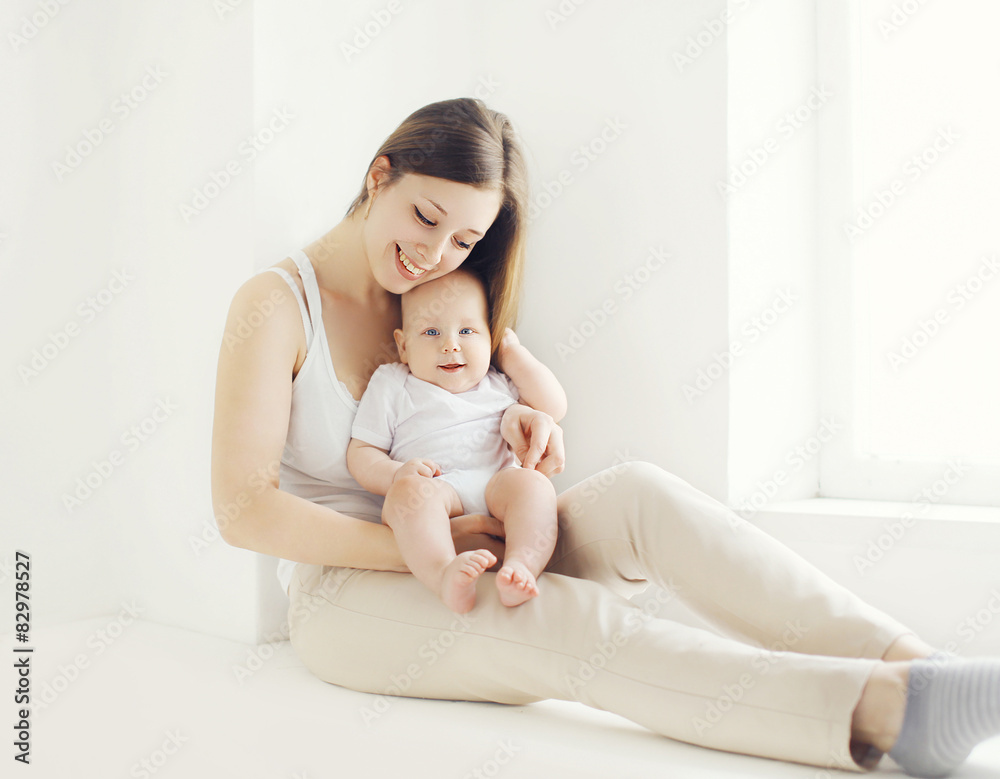 Happy young mother with baby at home in white room near window Happy young mother with baby at home in white room near window
