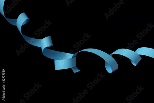 Twee gekrulde blauwe papieren stroken op een zwarte achter grond photo