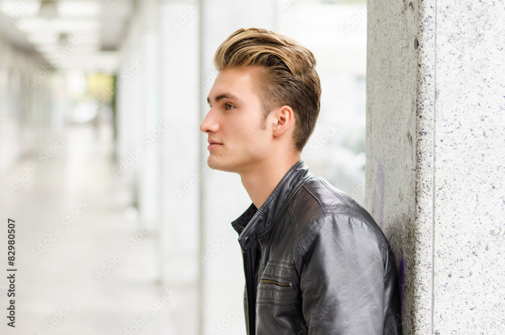 Attractive blond young man standing outside against pillar Attractive blond young man standing outside against pillar
