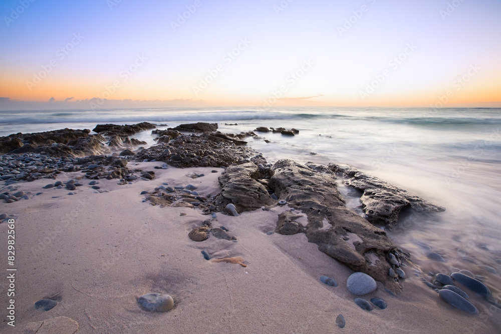 Late evening landscape of ocean over rocky shore with clouds blo Late evening landscape of ocean over rocky shore with clouds blo