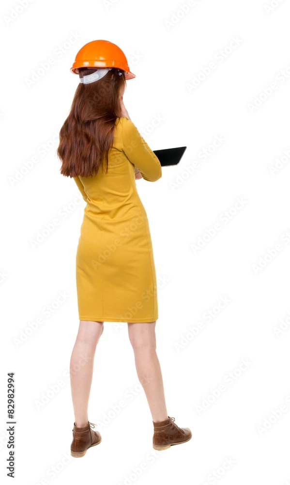 Backview of business woman in construction helmet stands and enj Backview of business woman in construction helmet stands and enj