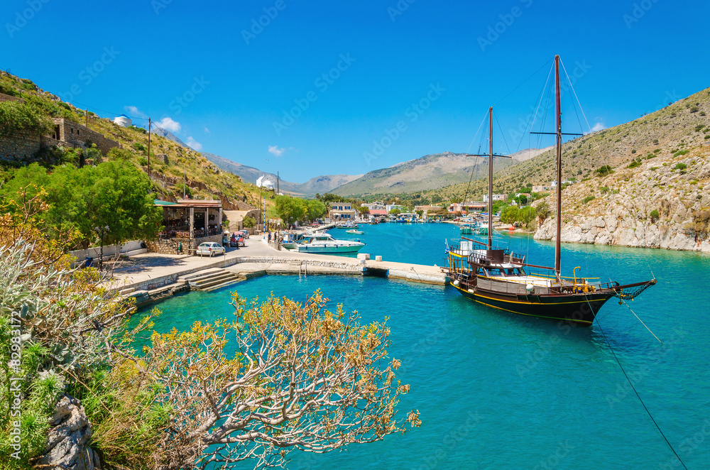Wooden yacht standing in cosy port on Greek island with clear bl