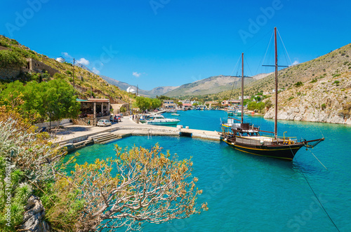 Wooden yacht standing in cosy port on Greek island with clear bl photo