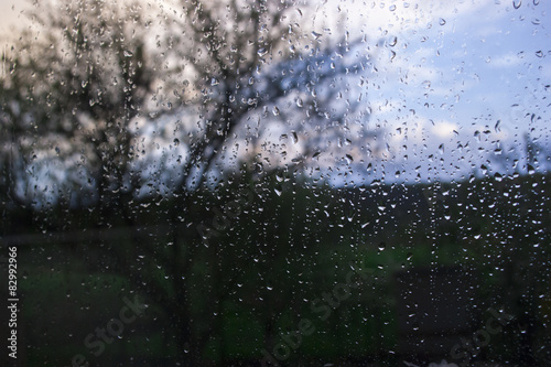 мокрое стекло с размытым деревом на фоне