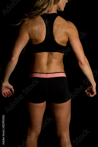 fit woman in black shorts and top on black arms down back