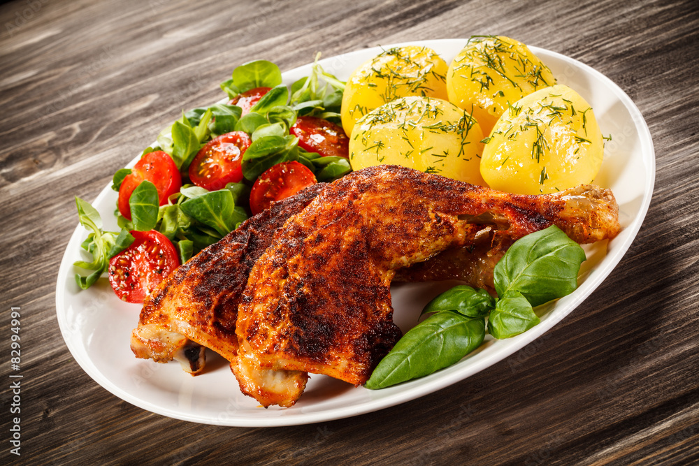 Barbecued chicken legs with boiled potatoes and vegetables 