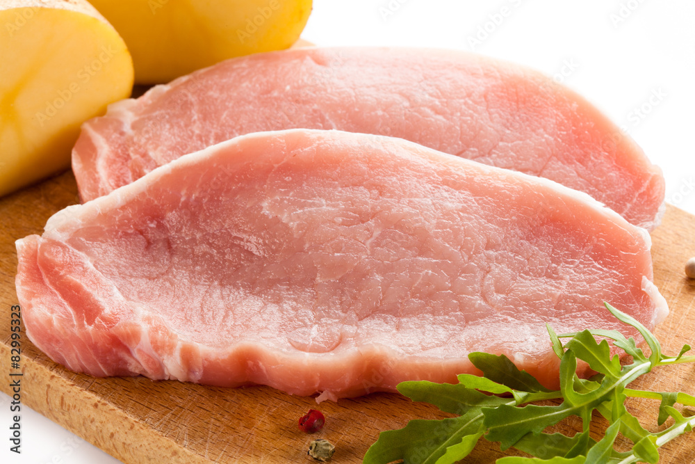 Raw pork chops on cutting board on white background Raw pork chops on cutting board on white background