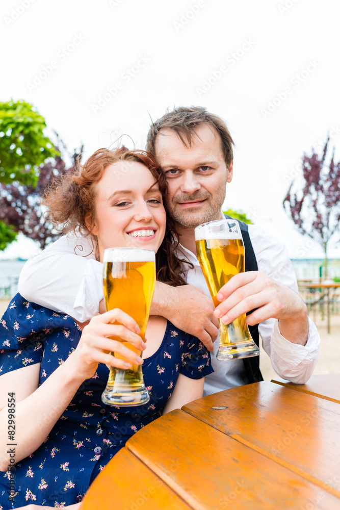 Verliebtes Paar prosten mit Bier im Biergarten Verliebtes Paar prosten mit Bier im Biergarten