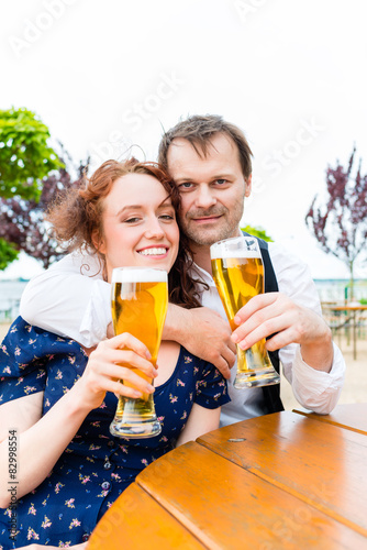 Verliebtes Paar prosten mit Bier im Biergarten 