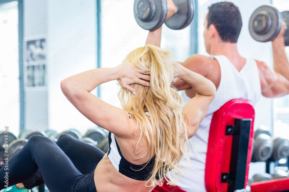 Obraz premium Friends lifting weights in fitness gym