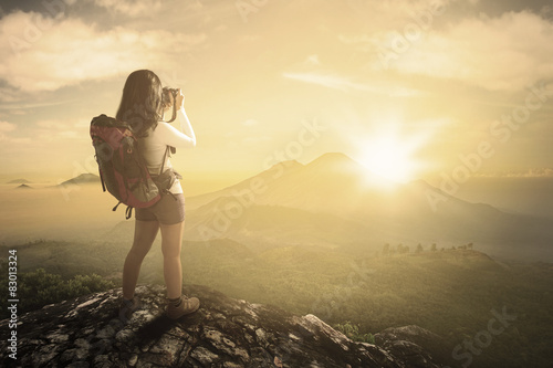 Female backpacker taking photo at mountain