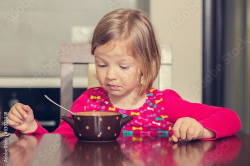 Beautiful little girl eating soup.