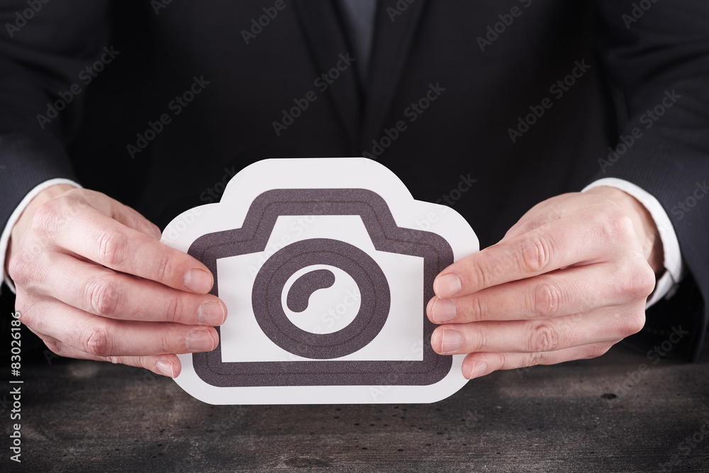 Man holding camera icon in hands