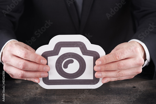 Obraz na płótnie Man holding camera icon in hands w salonie