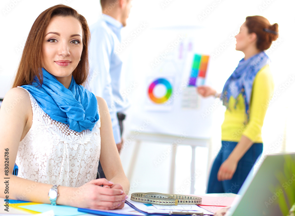 Portrait of attractive female designer sittin on thesk in Portrait of attractive female designer sittin on thesk in