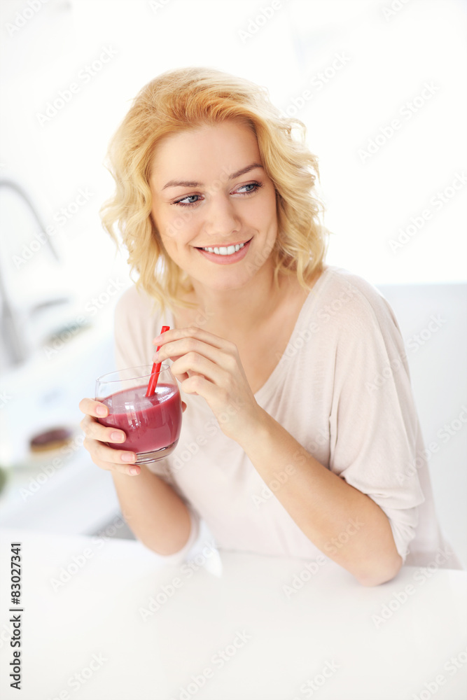 Young woman drinking smoothie in the kitchen Young woman drinking smoothie in the kitchen
