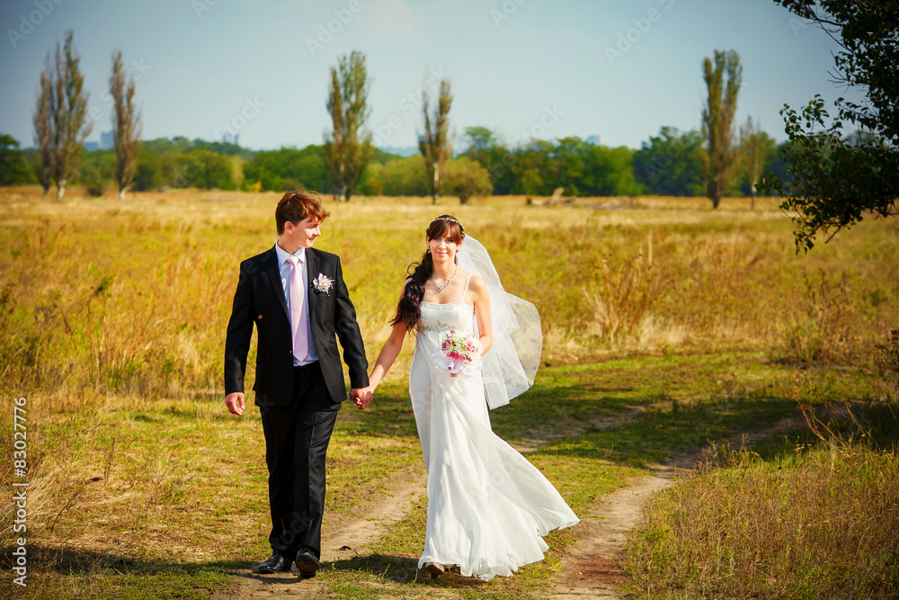 young bride and groom walking in a beautiful garden holding hand