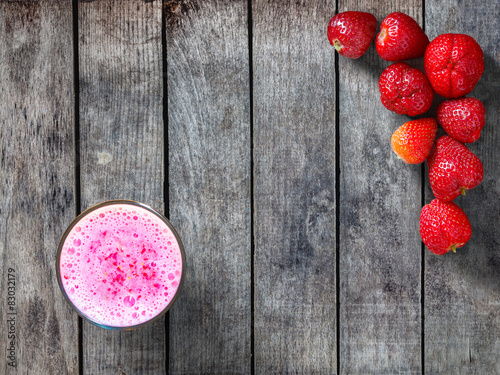 Strawberries and a glass of smoothie on a wooden background