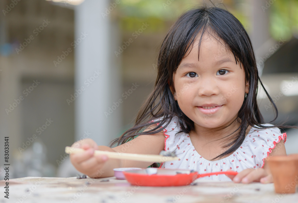Smiling little girl plays cook on the table Smiling little girl plays cook on the table