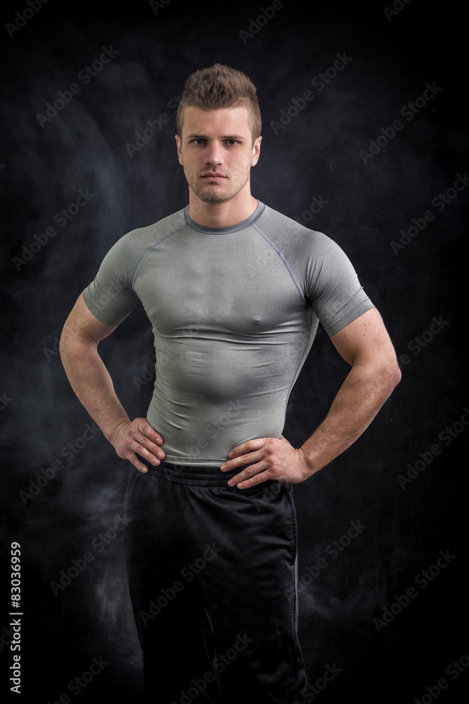 Naklejka premium Portrait of handsome young man in grey t-shirt on black 