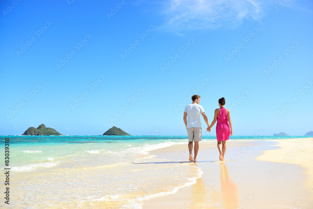 Beach couple holding hands walking on Hawaii