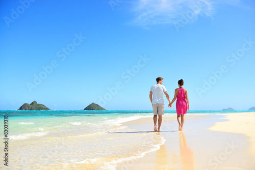 Beach couple holding hands walking on Hawaii
