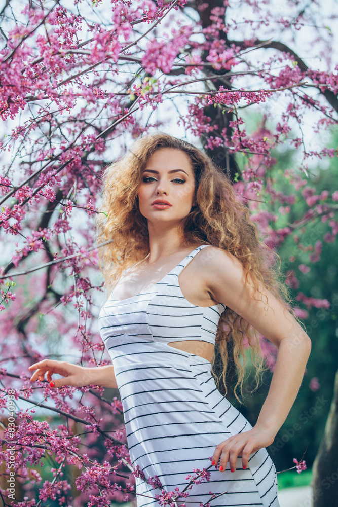 Beautiful young woman with gorgeous curly fair outdoors