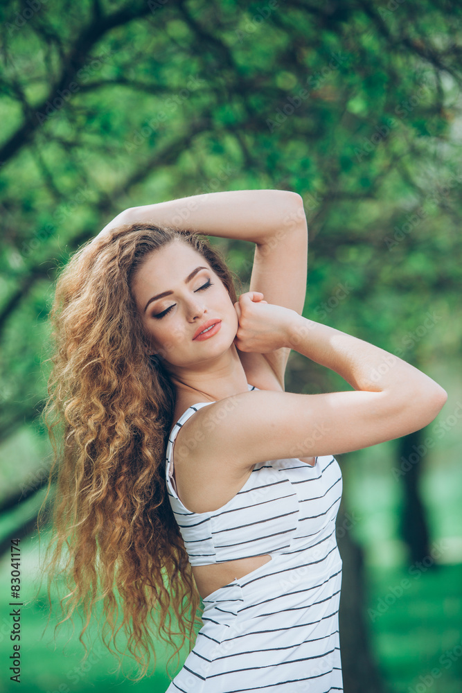 Fototapeta premium Beautiful young woman with gorgeous curly fair outdoors