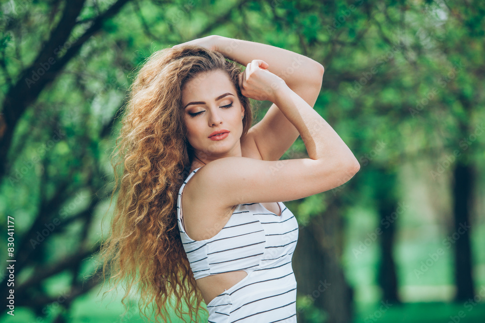 Naklejka premium Beautiful young woman with gorgeous curly fair outdoors
