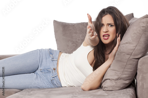 angry young woman lying on the couch and complains