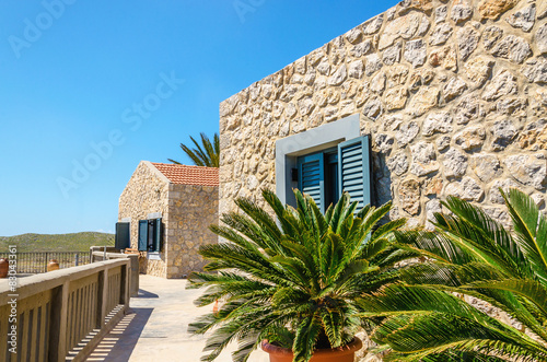 Typical wall for old Greek buildings with palm trees in foregrou