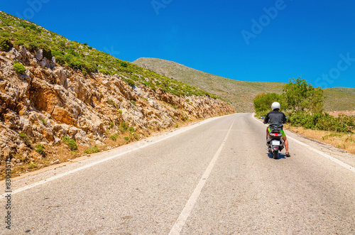 Young man driving scooter on empty asphalt road, Greek Island Ka