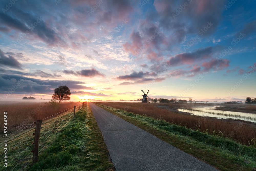 beautiful sunrise on dutch farmland with windmill