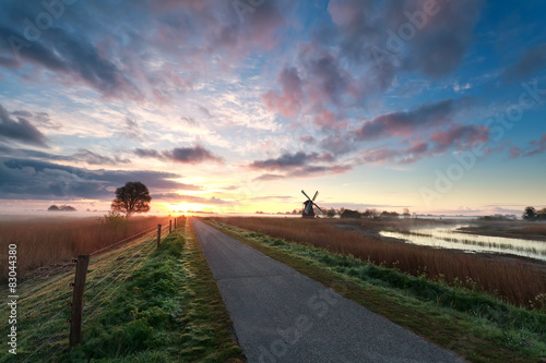 beautiful sunrise on dutch farmland with windmill