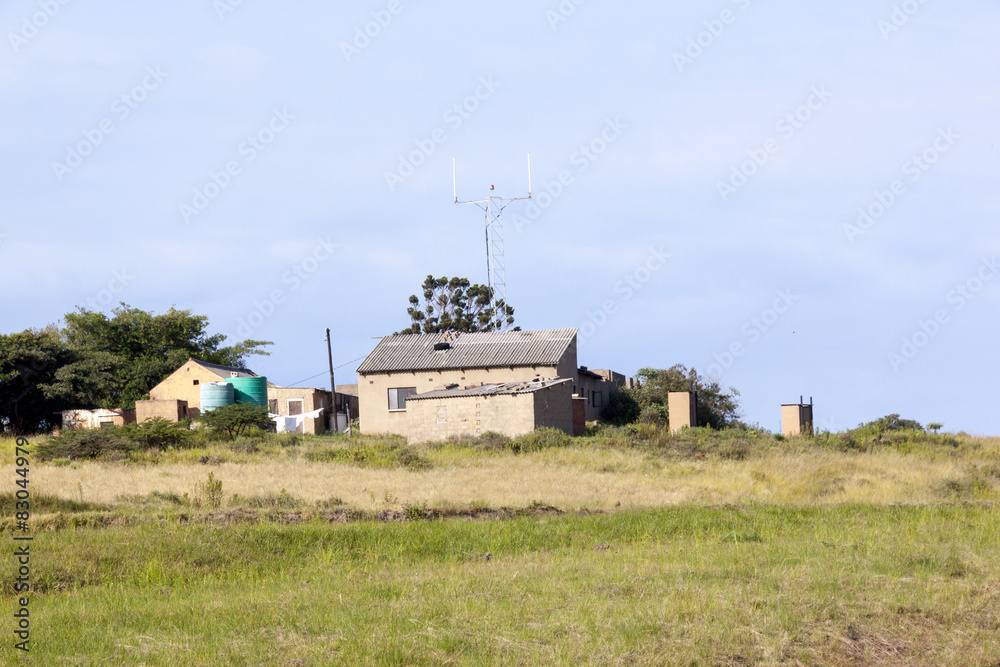 Fototapeta premium Open Grassland with Rural Farm Buildings in Background