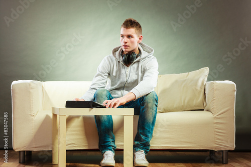 man with headphones sitting on couch with tablet