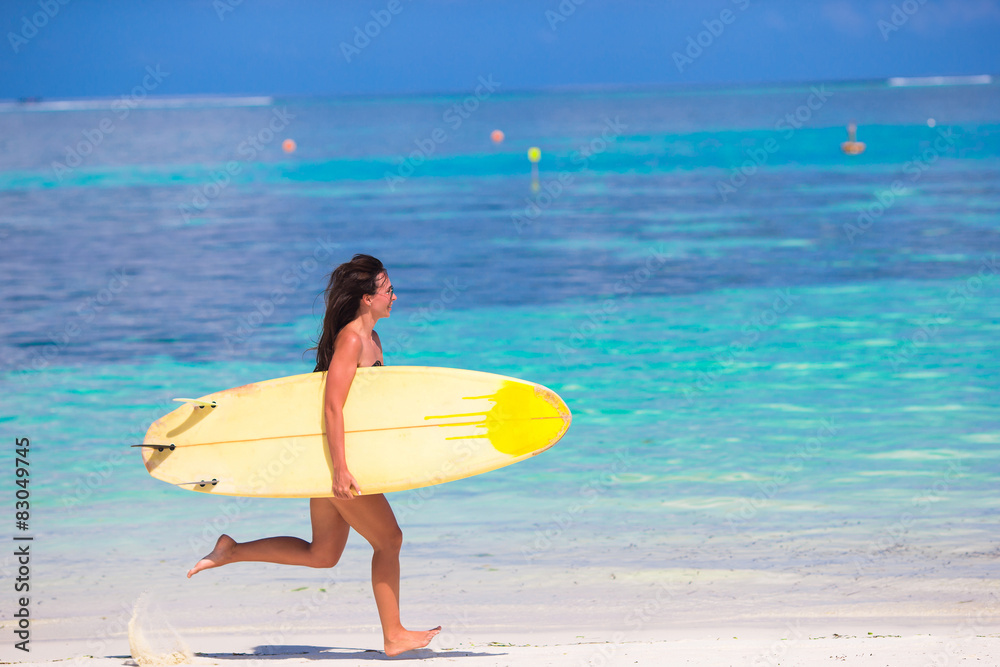 Happy young surf woman runing at the beach with a surfboard