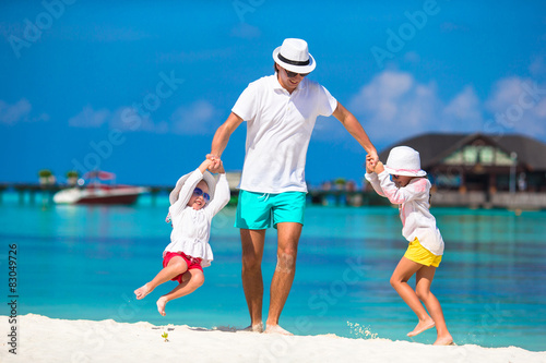 Happy father and his adorable little daughters at tropical beach