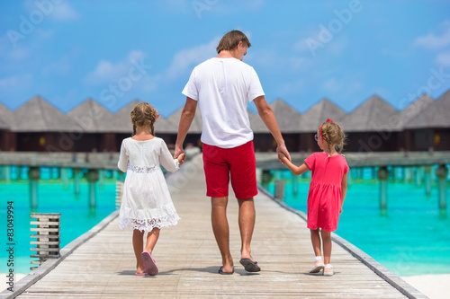 Little girls with dad on wooden jetty near water bungalow at © travnikovstudio