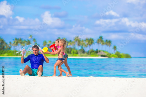 Adorable little girls having fun with dad on white beach
